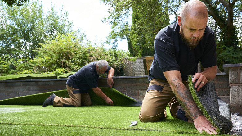 Two men doing a fake lawn installation 