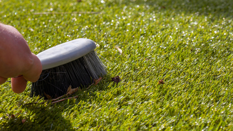 Brushing leaves off a fake lawn