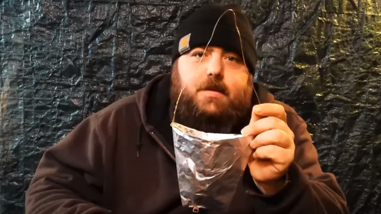 Man holding cup made of aluminum foil