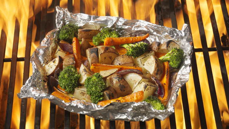 Vegetables on aluminum foil over flamed grill