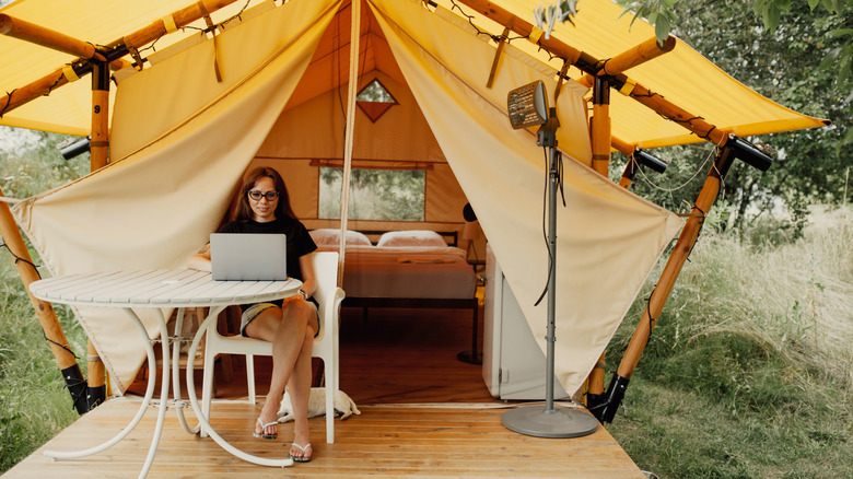 Woman working on laptop in aesthetic campsite setup