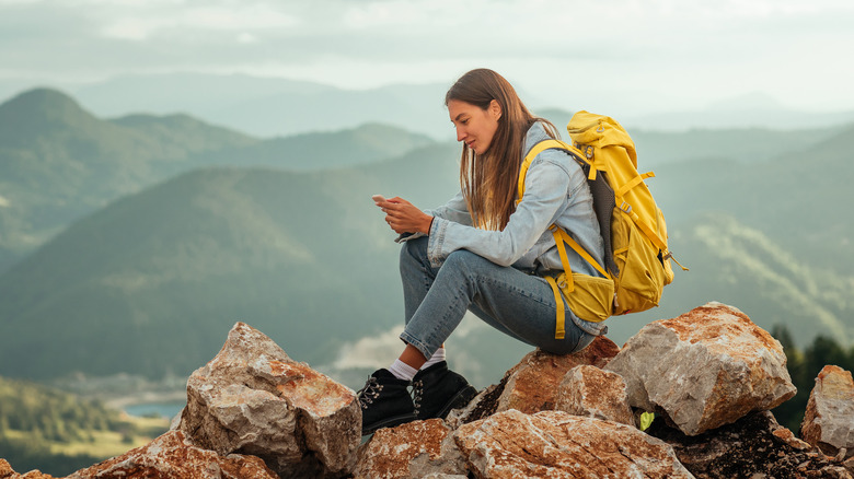 Female hiker texting at the top of a mountain