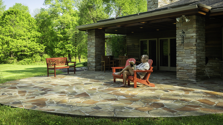 Man reading in chair on stone patio