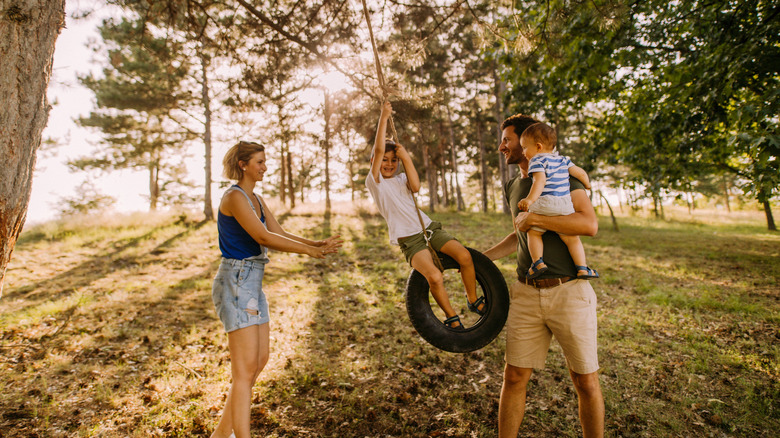 Family playing on tire swing outside