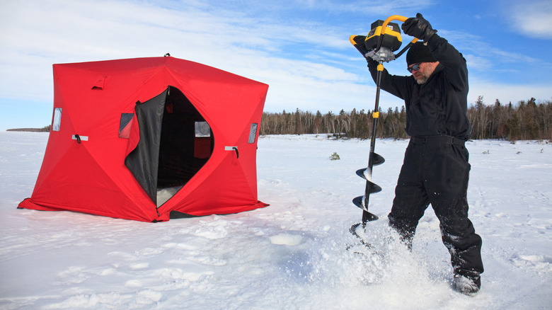 Ice fisherman drilling hole into snow and ice