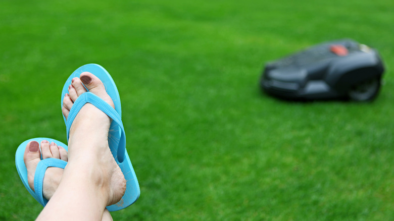 Person's feet next to robot lawn mower in background
