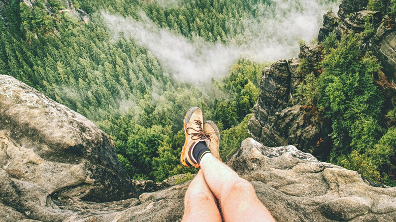 Person's legs on rocks with forest underneath