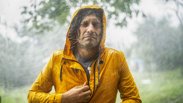 Miserable man in rain coat caught in downpour