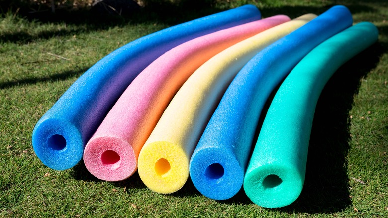 Colorful pool noodles on grass