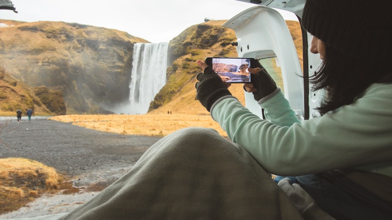 Camper taking photo of waterfall from inside of van