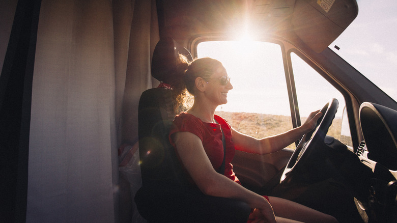 Female camper driving RV with sun shining