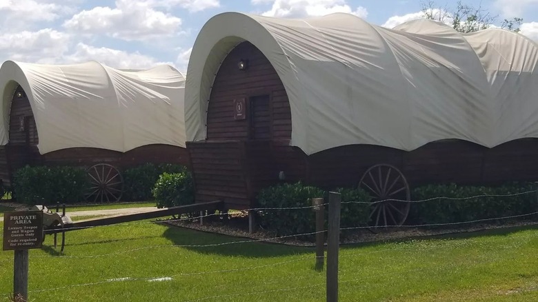 Couple posing in front of glamping pioneer wagon