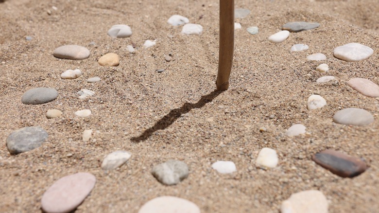 Improvised sundial made of stick sand stones