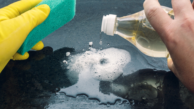 person using vinegar to clean surface