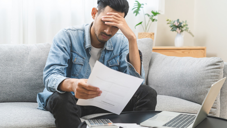 Stressed man with laptop, calculator, and paper