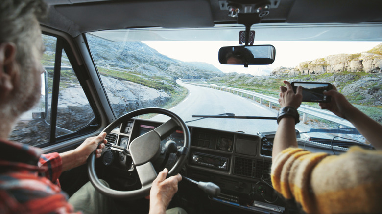 Man driving RV while another person takes picture