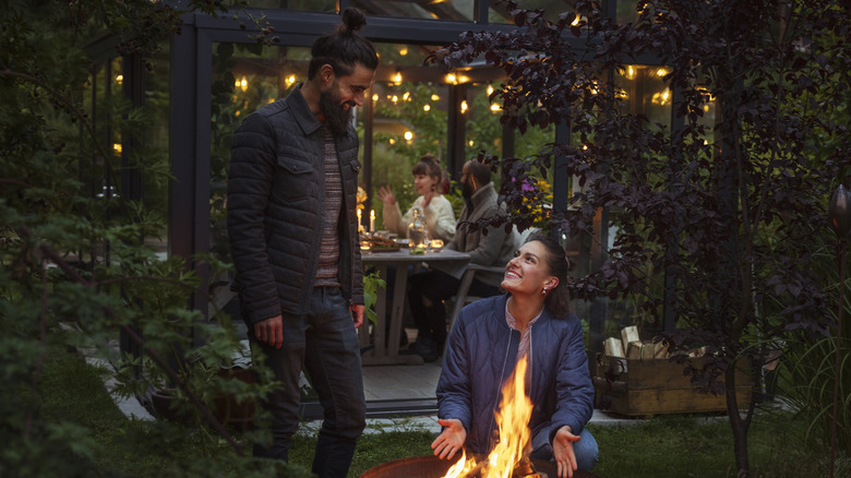 Man and woman smiling in front of firepit