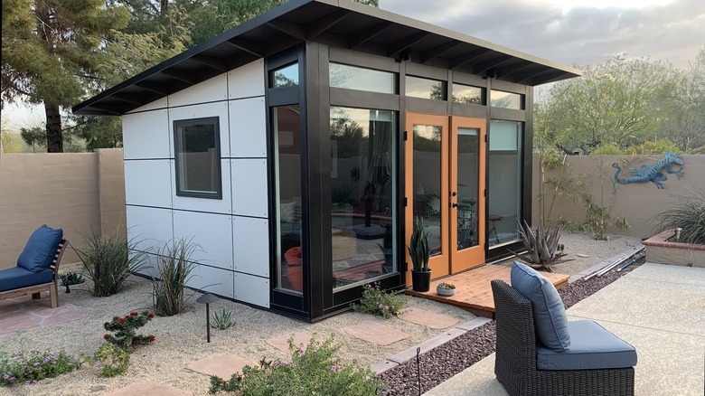 A black, brown, and white shed from Studio Shed in a backyard