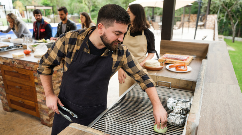 Group of friends grilling in an outdoor kitchen.