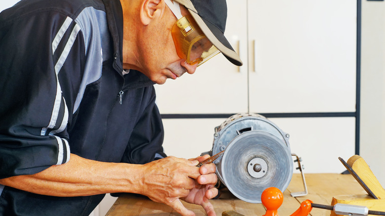 Man sharpening tools on a bench grinder