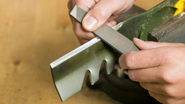Pair of hands sharpening blades with a file