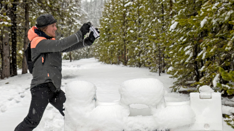 Woman discharging bear spray in snowy forest