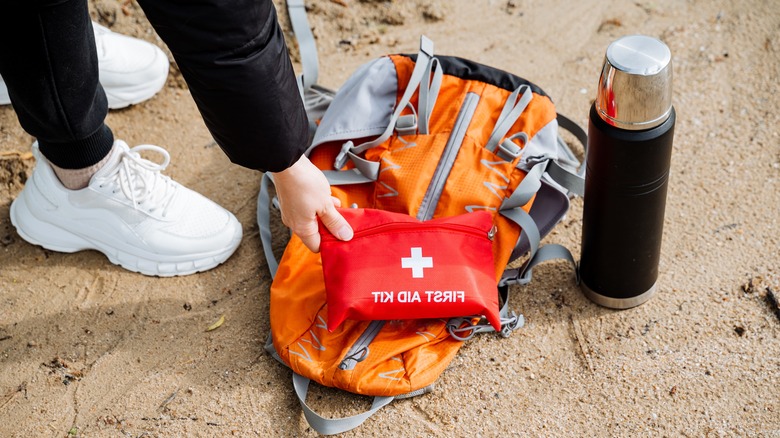 Hiker reaching for first aid kit on ground