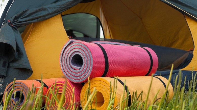 Rolled closed cell sleeping pads in front of tent