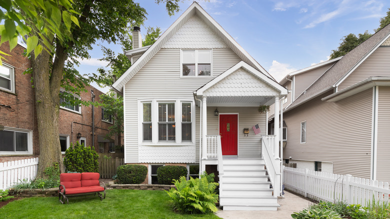 House with a manicured small yard and red bench