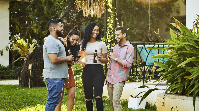 A group of friends outside drinking wine and beer and laughing