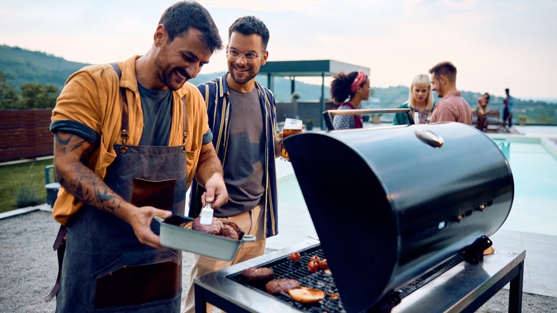 Smiling man grilling with friends