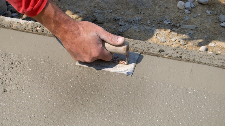 Man's hand smoothing out the edge of concrete