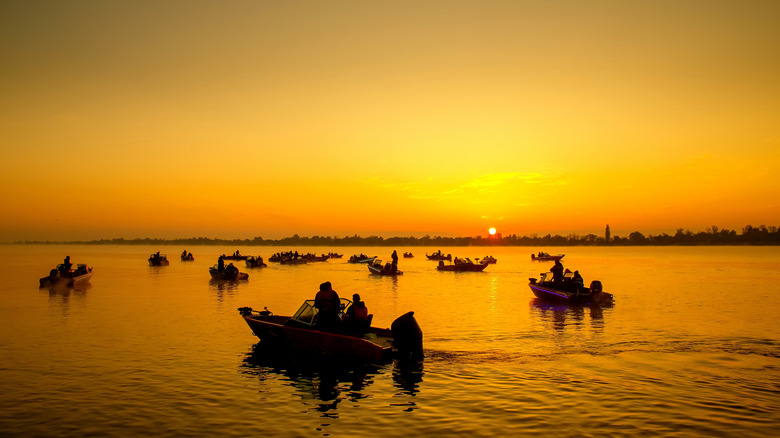 Fishermen in multiple boats in the water at sunset