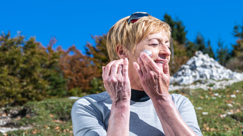 Woman applies sunscreen outdoors