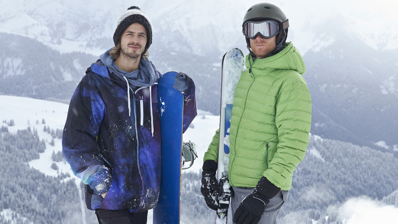 Snowboarders posing on mountain with boards