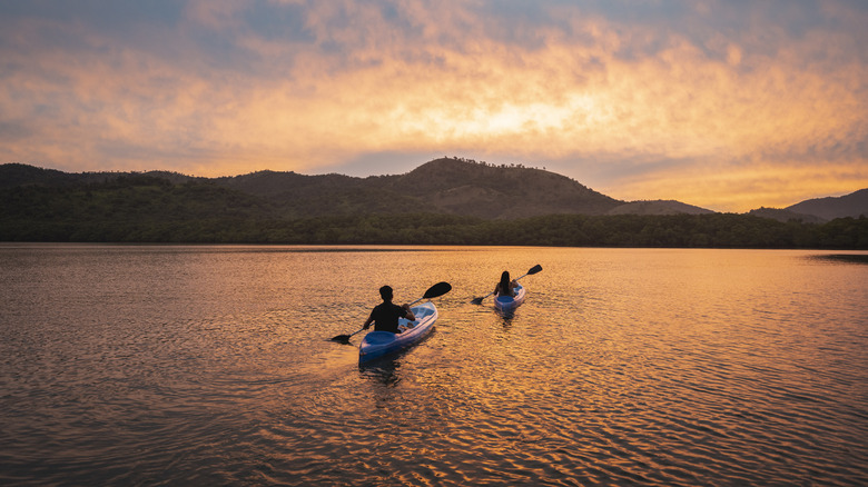 Two people kayaking into the sunset