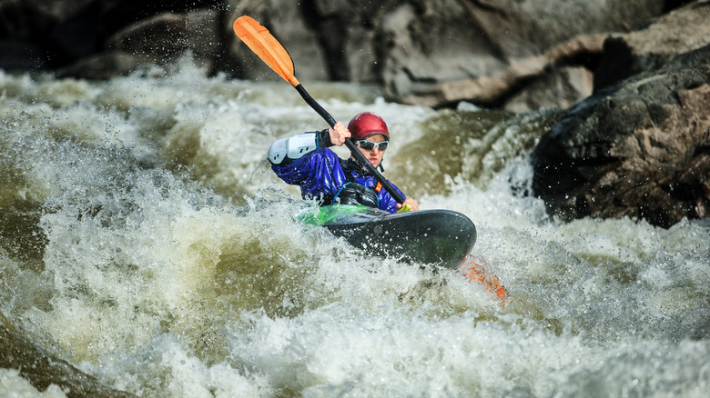 Person paddling heavy waves in whitewater kayak