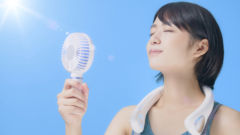 Woman using fans to cool off