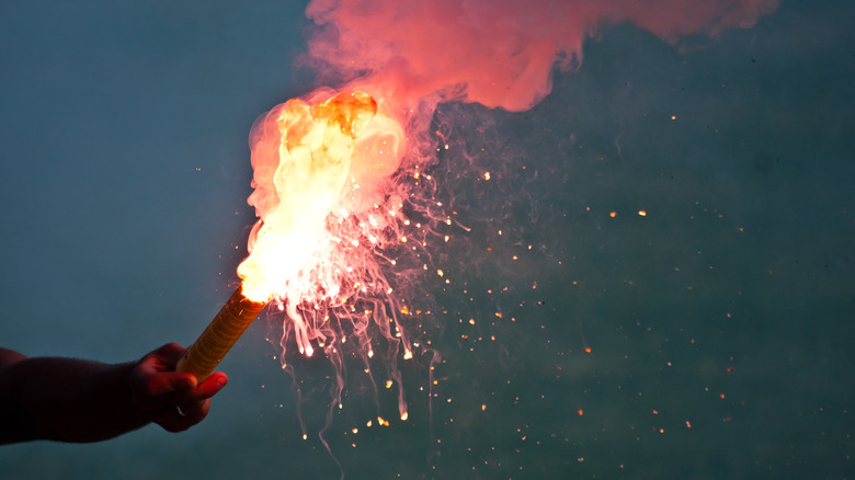 Hand holding emergency flare at night