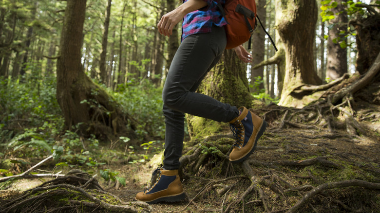 Person hiking through the woods, focus on lower body