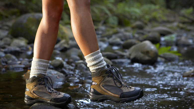 Person walking across stream in hiking boots, focus on feet