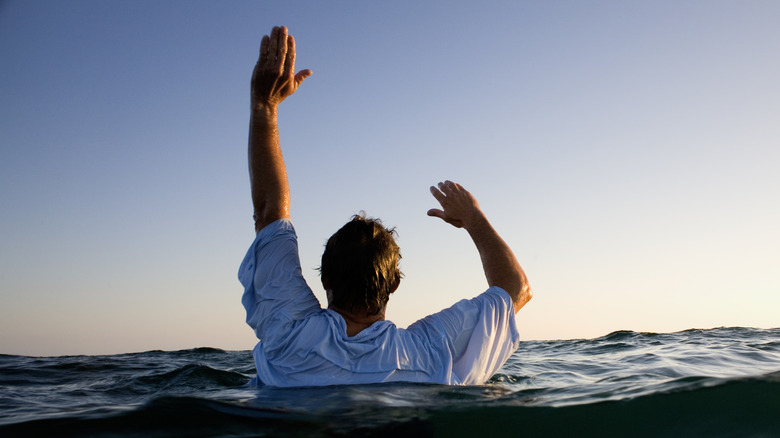 man in water with hands raised