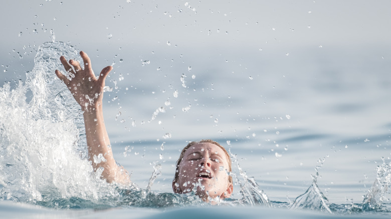 panicked person in water with hand raised