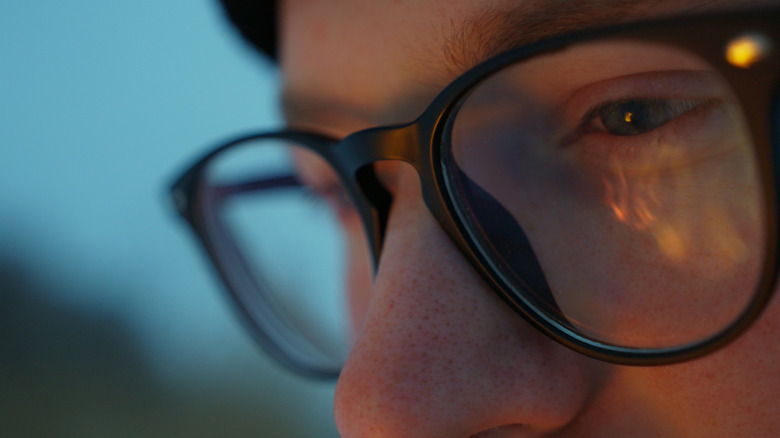 Close-up of face with fire reflected in eye glasses