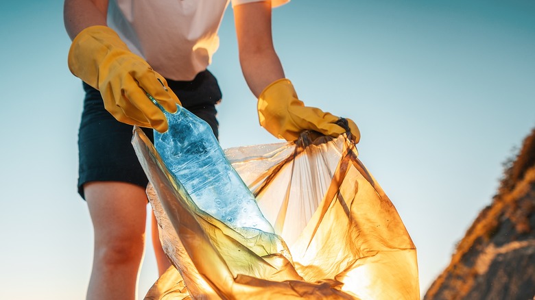 Woman putting plastic into trash bag