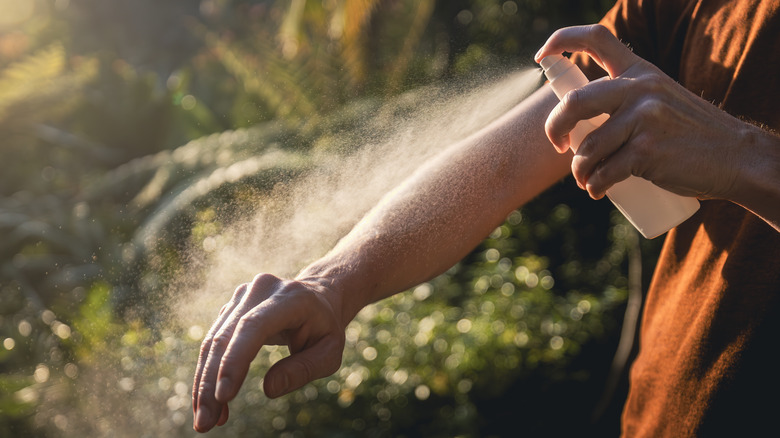 Hand spraying rubbing alcohol on arm