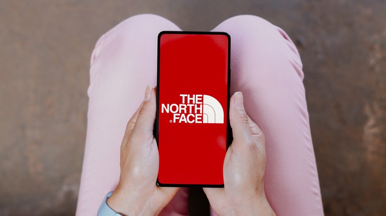 Person holding phone with The North Face logo on screen