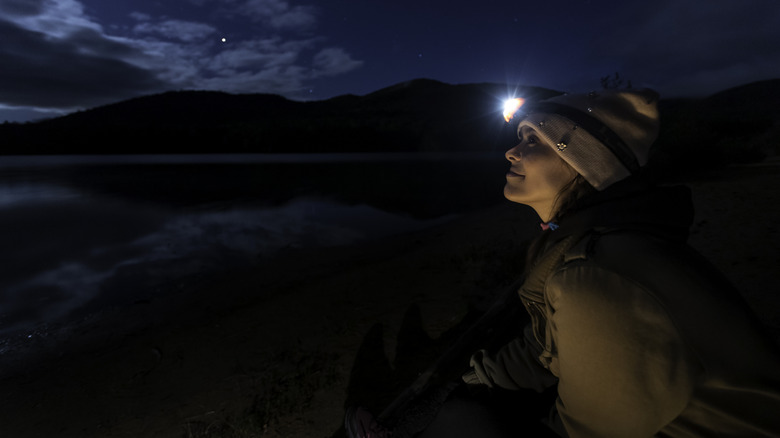 Woman wearing headlamp, looking up at the sky