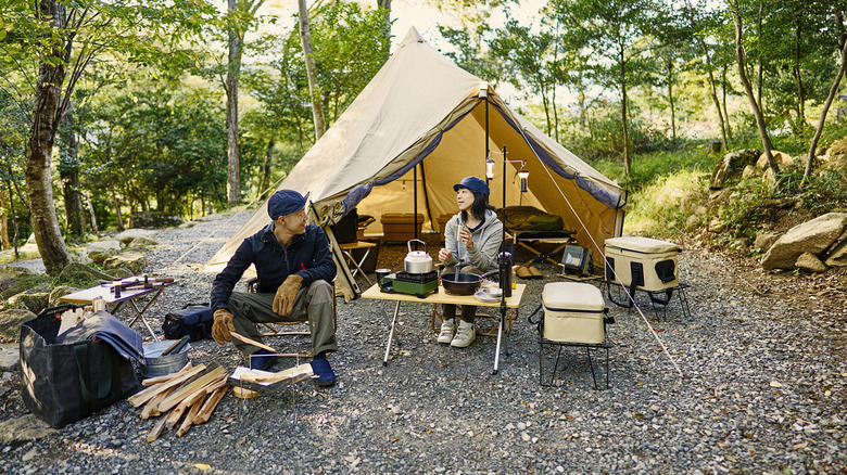 Man and woman sitting outside tent at a campsite