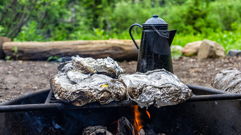 Aluminum foil wrapped food on camp grill 